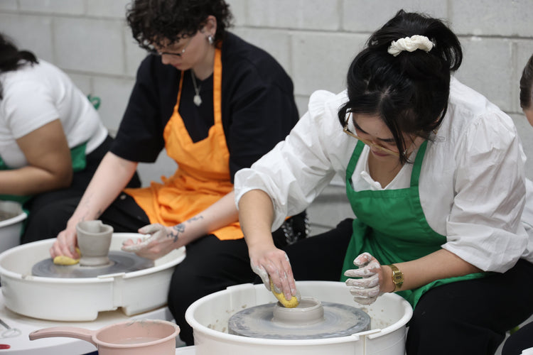 on a pottery wheel using am sponge to smooth out a ceramic bowl